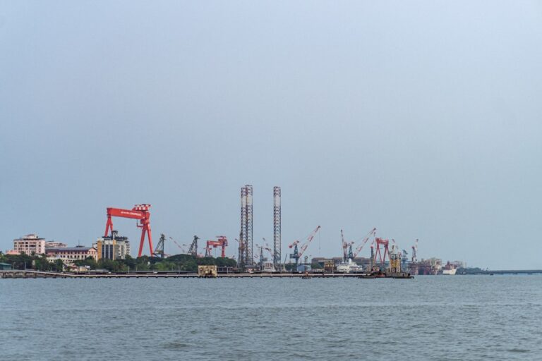An industrial port with cranes and structures seen across water.