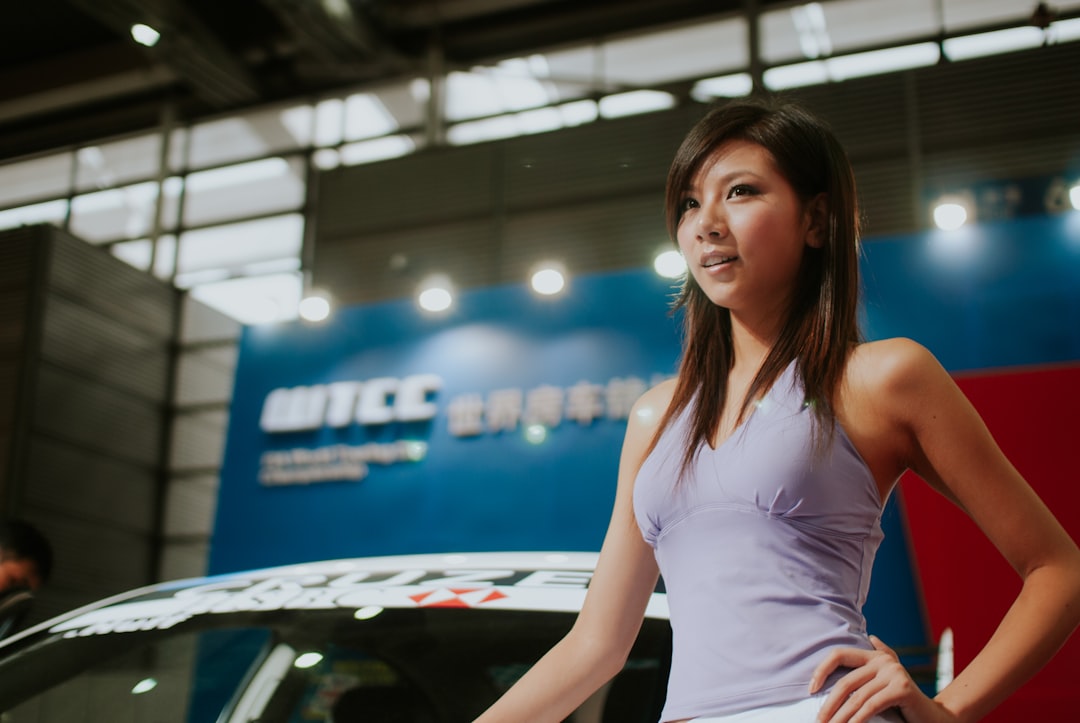 A woman in a purple top poses by a car.