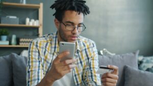 Man holding credit card and phone for online shopping.