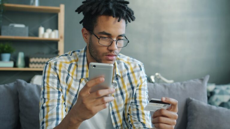 Man holding credit card and phone for online shopping.