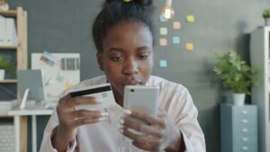 Woman holding credit card and smartphone for online shopping.