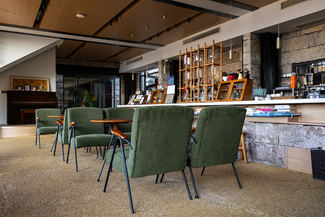 Cozy cafe interior with green chairs and wooden tables.