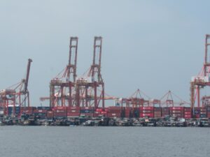 Large cranes and shipping containers at a busy port.