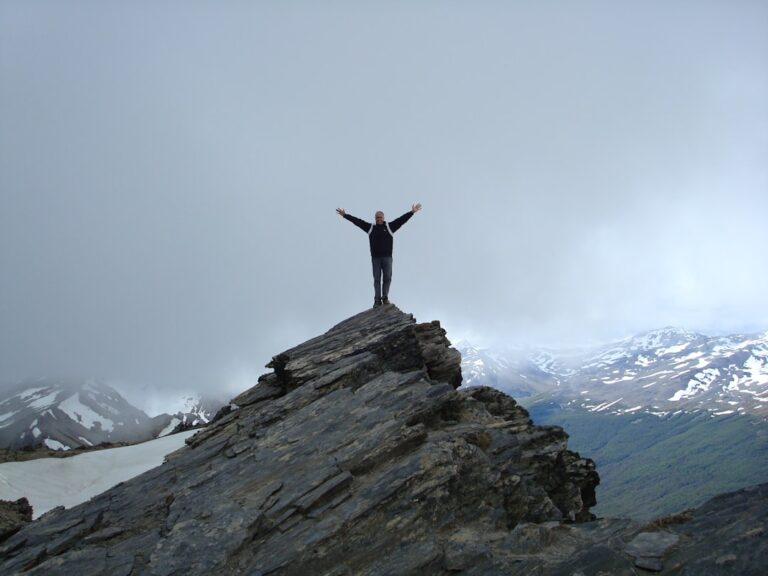 a man standing on top of a mountain with his arms wide open