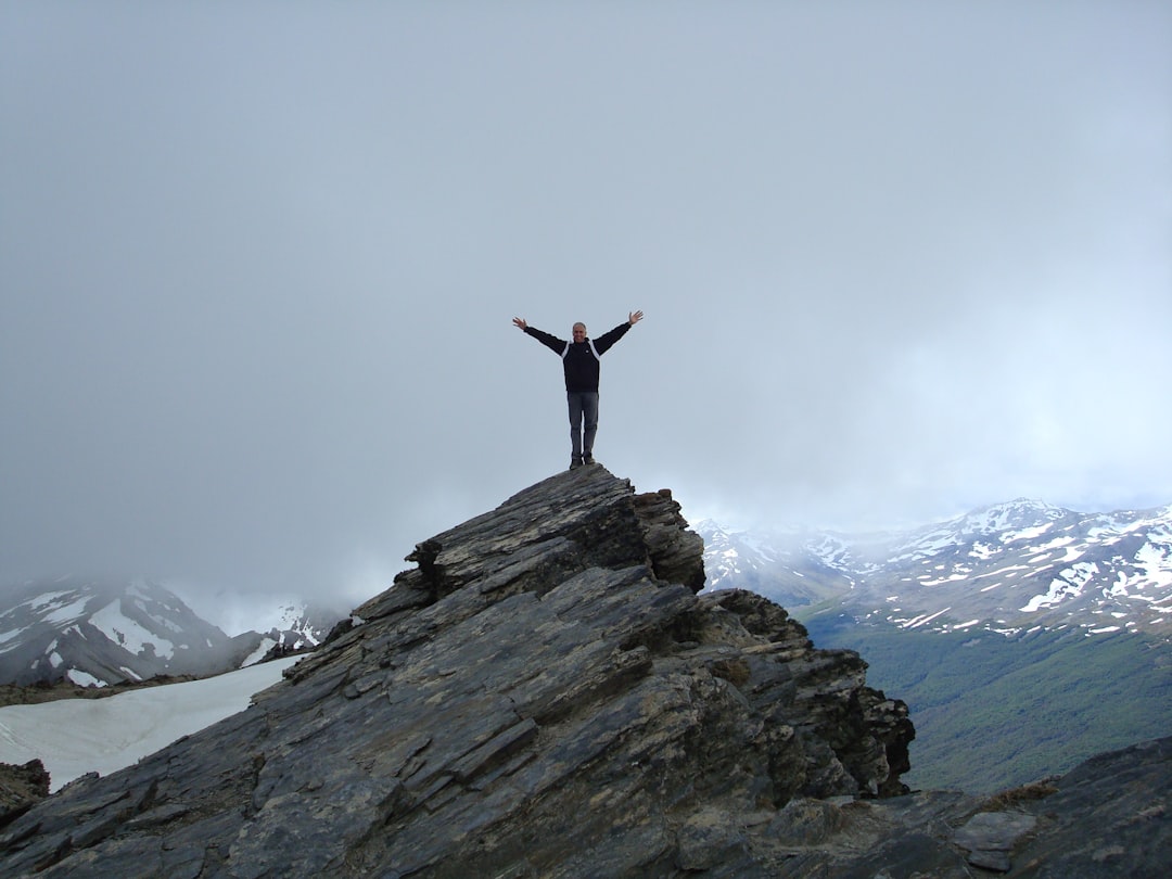 a man standing on top of a mountain with his arms wide open
