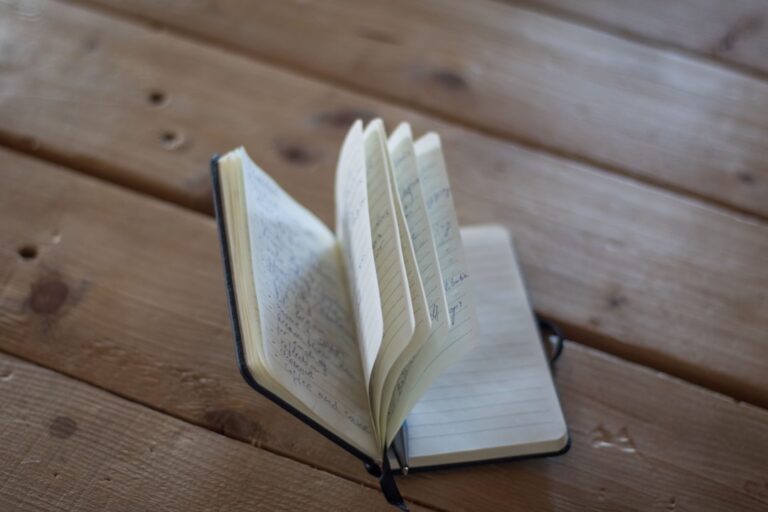 An open notebook with pages fluttering on a wooden surface