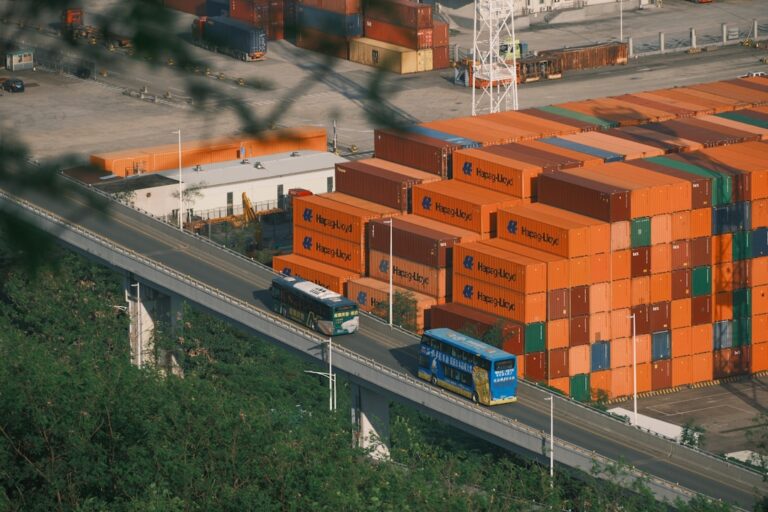Orange shipping containers stacked at a busy port.