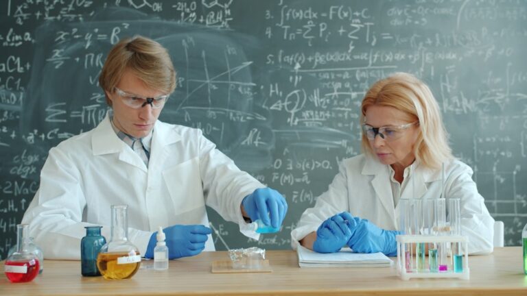 Scientists in lab coats conduct experiment with beakers.