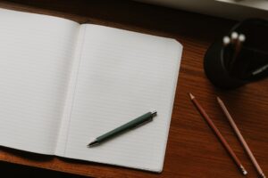 Open notebook with pen and pencils on desk