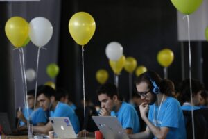 a group of people sitting at a table with laptops