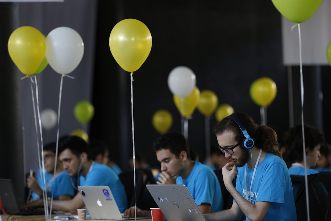 a group of people sitting at a table with laptops
